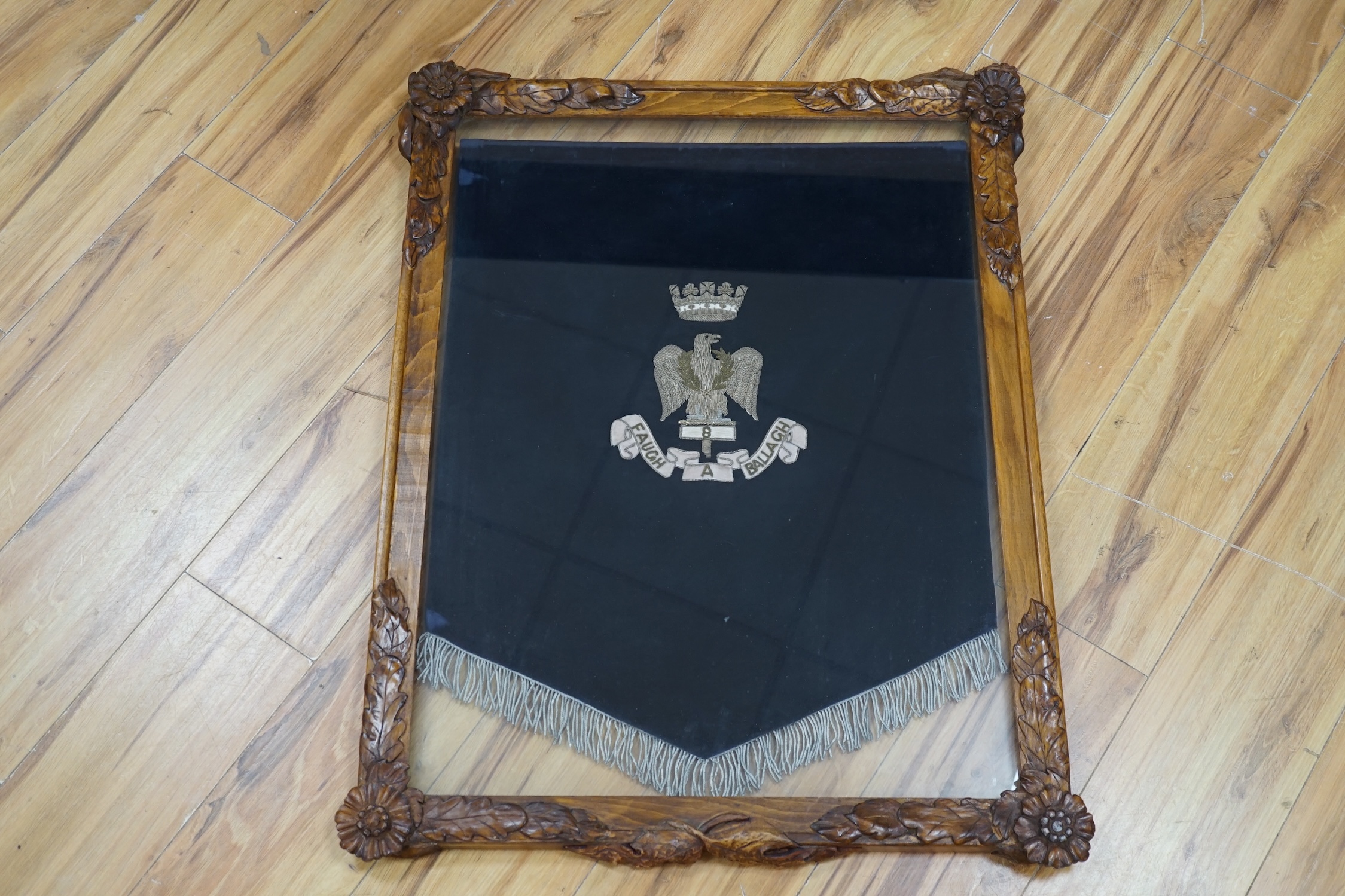 A framed bandsman’s banner of the Royal Irish Fusiliers, a crowned eagle in silver thread, over ‘8 Faugh A Ballagh’, 64 x 52cm, in a carved oak frame. Condition - good.